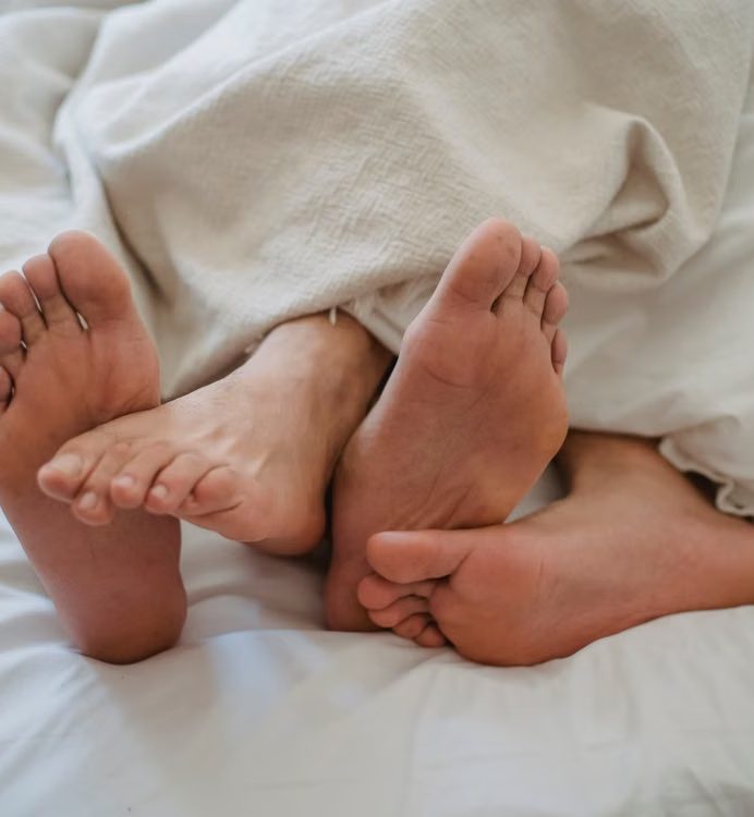 Pies descansando en la cama al final de la jornada